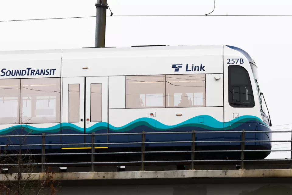 White and blue Sound Transit light rail train on elevated rail in Seattle, Washington.